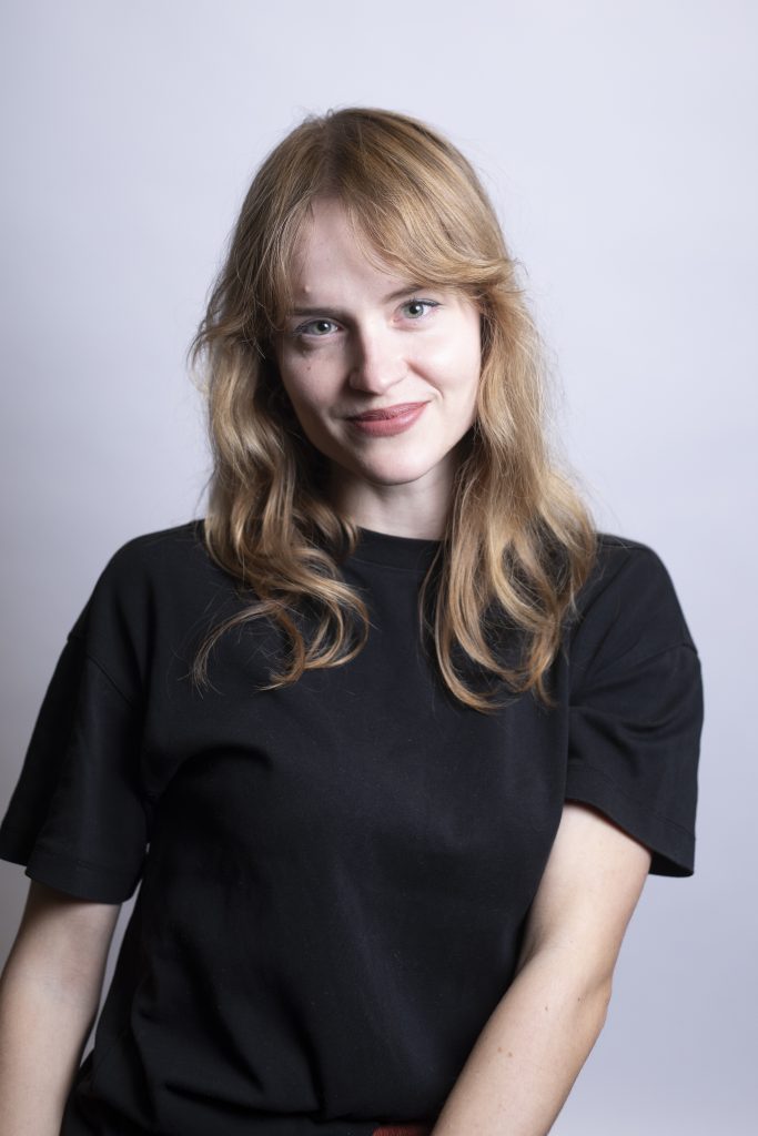 Mujer sonriendo con camisa negra, fondo de estudio.
