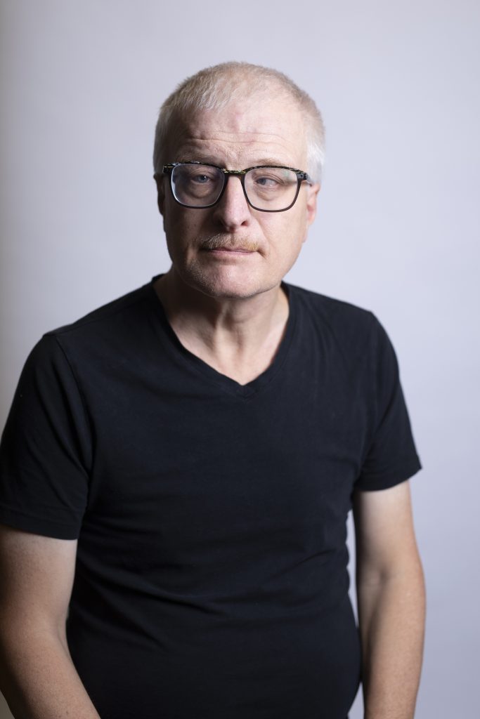 Hombre de mediana edad con gafas y camisa negra.