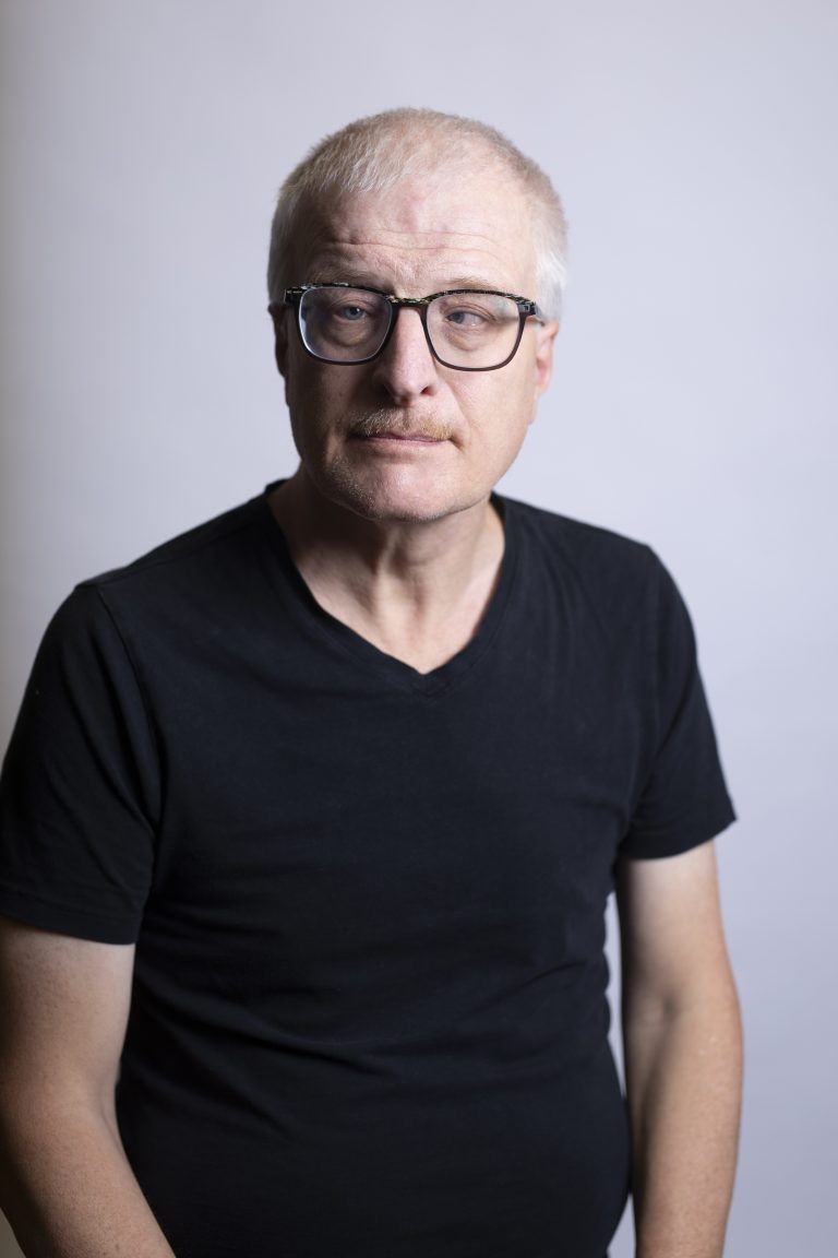 Hombre de mediana edad con gafas y camisa negra.