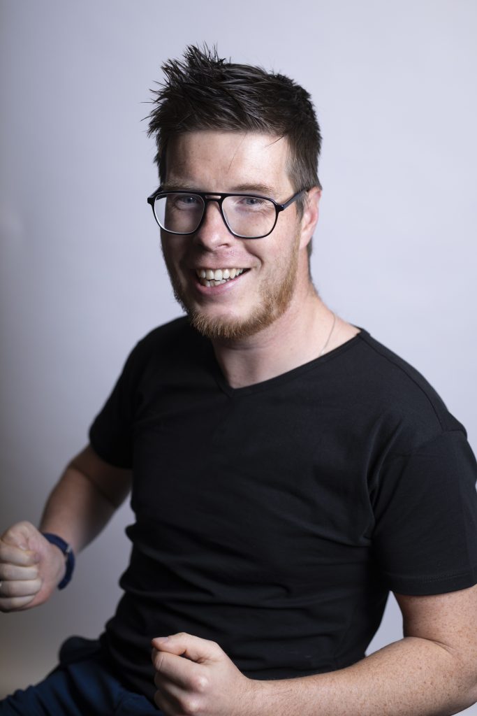 Hombre sonriente con gafas y camisa negra.