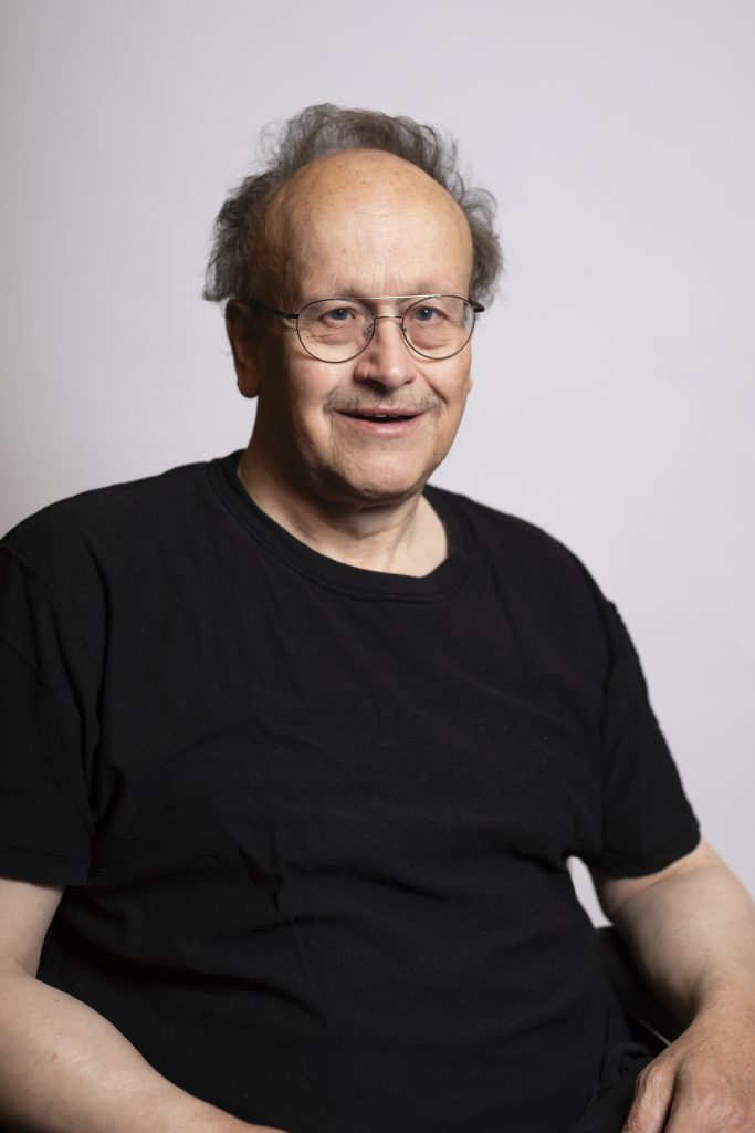 Hombre con camisa negra y gafas sonriendo.